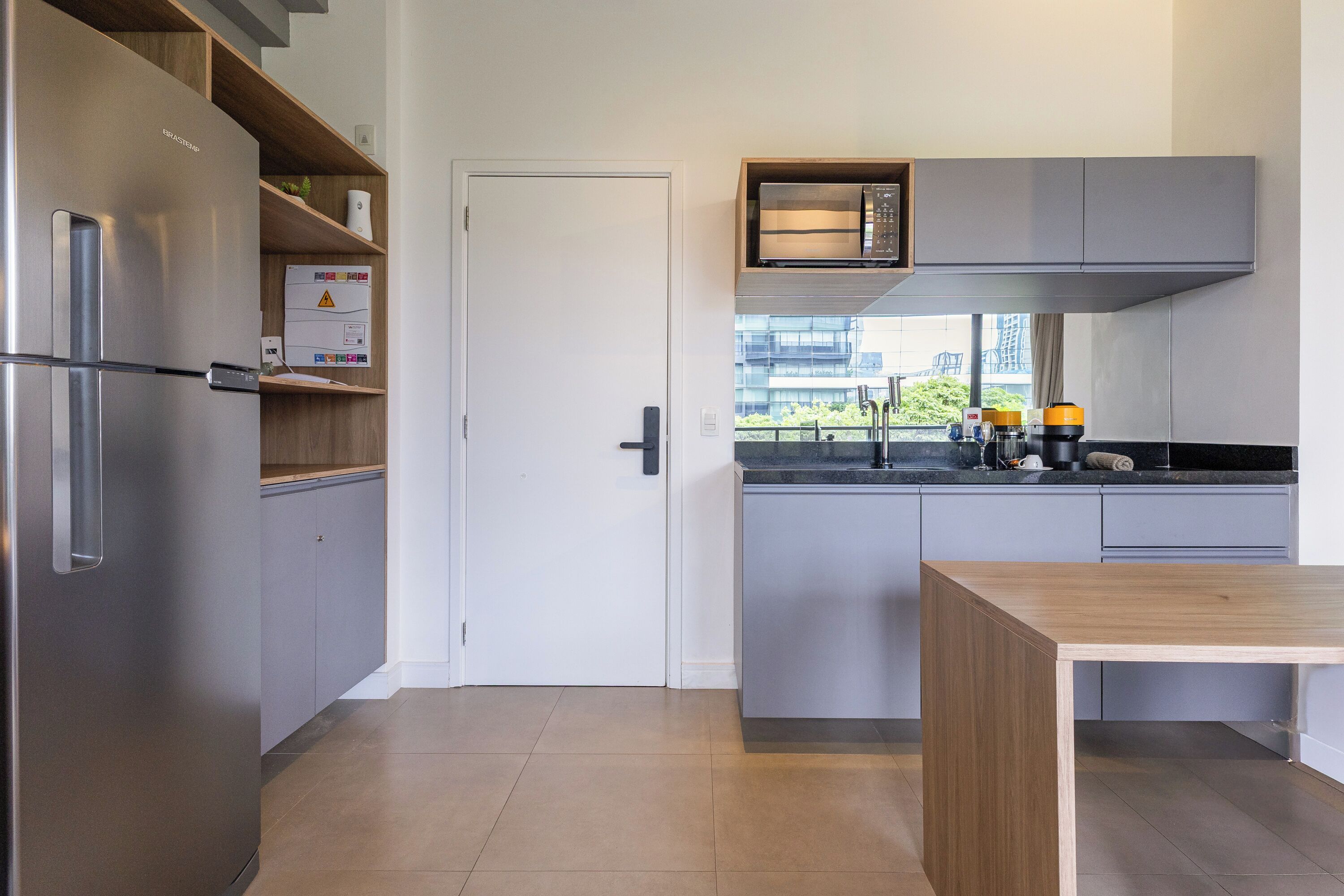 Una cocina moderna con un refrigerador empotrado, un microondas y una cafetera.