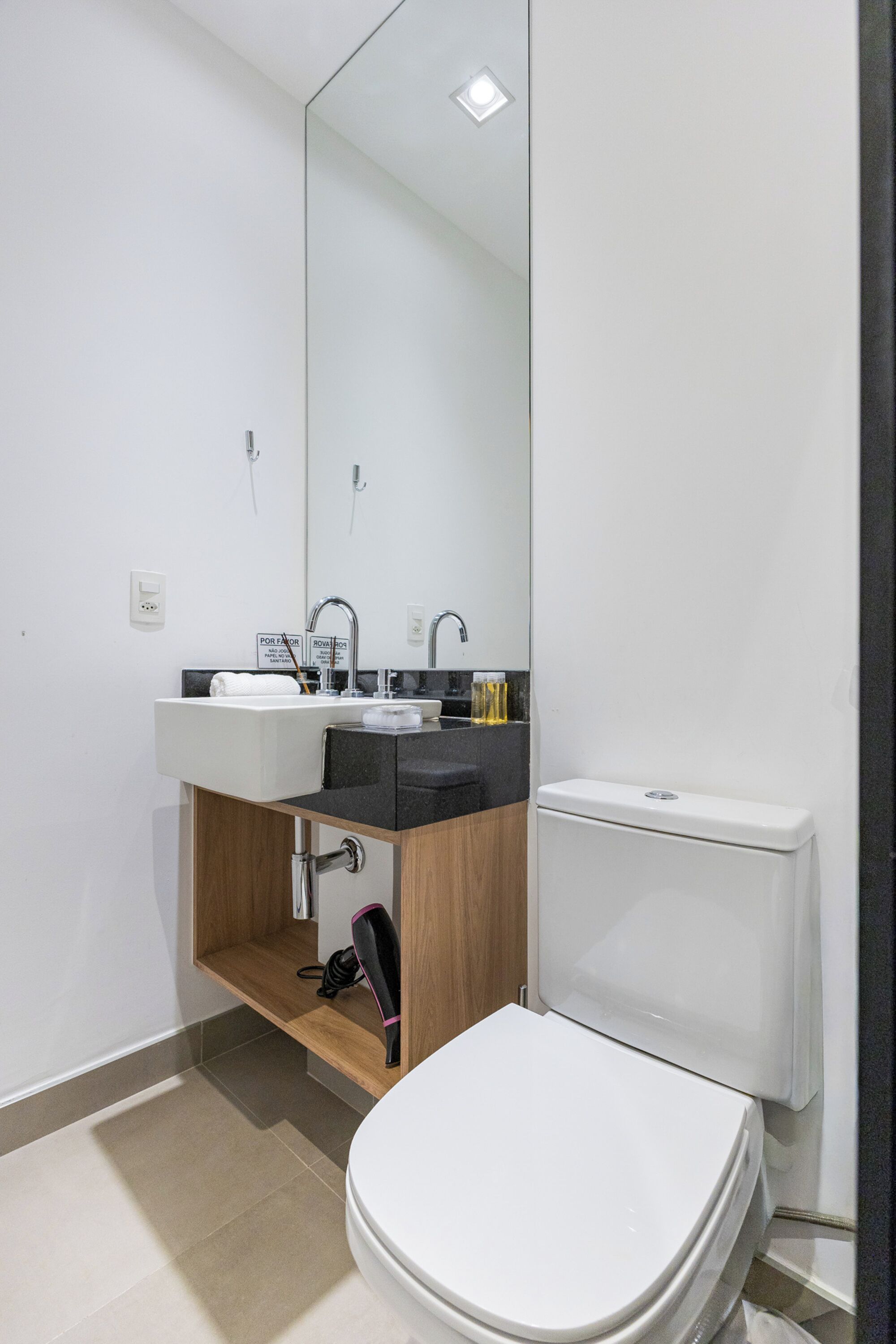 A modern bathroom with a white sink, mirror, and toilet.