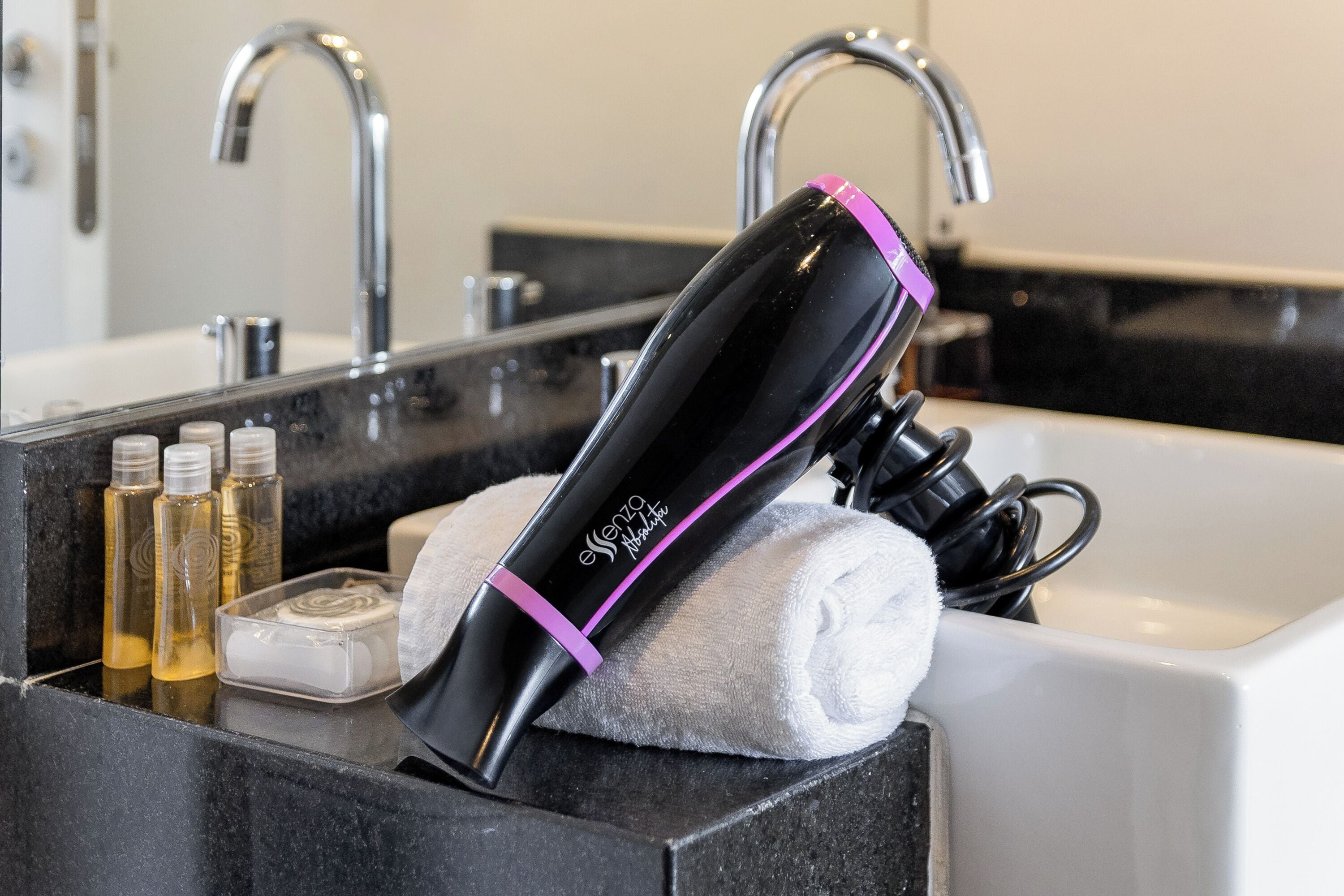 A bathroom with a black countertop, a white towel, and a hairdryer.