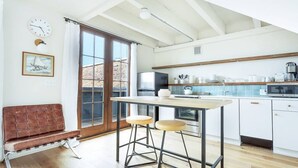 A modern kitchen with a large window, a dining area with stools, and a bench. - The Windrose (Savannah)