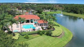 Una casa grande con piscina, rodeada de abundante vegetación y un lago.