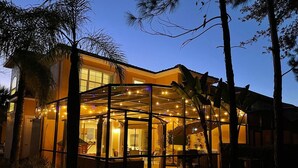 Een modern huis met een glazen patio, een open keuken en een eethoek.