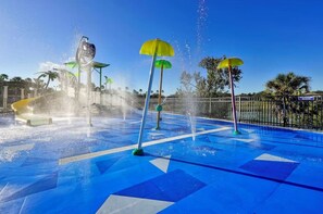 Ein Wasserpark mit zahlreichen Wasserstrahlern und bunten Sonnenschirmen.