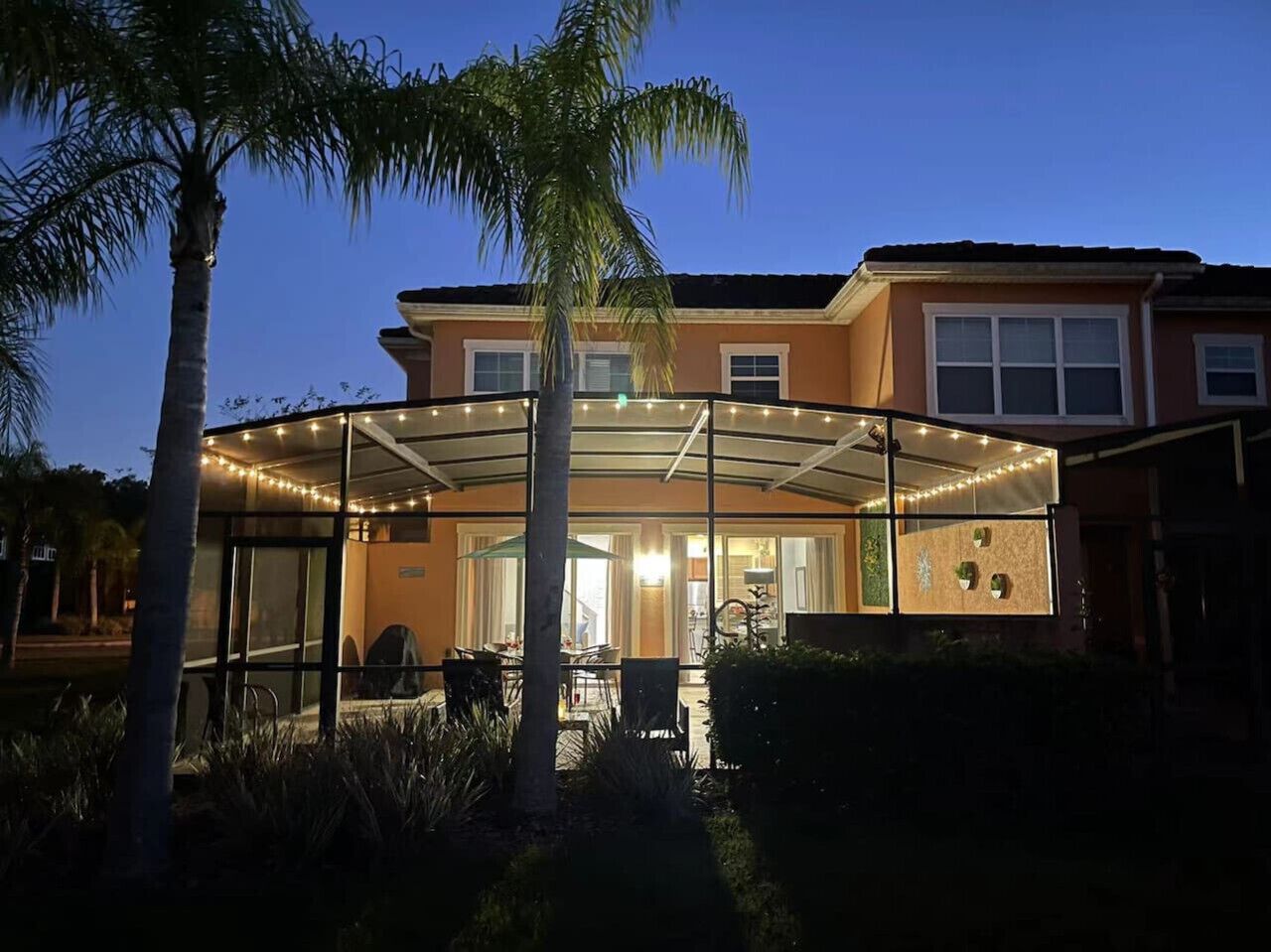 Une maison dotée d’un patio couvert, d’une piscine et d’une entrée bien éclairée.