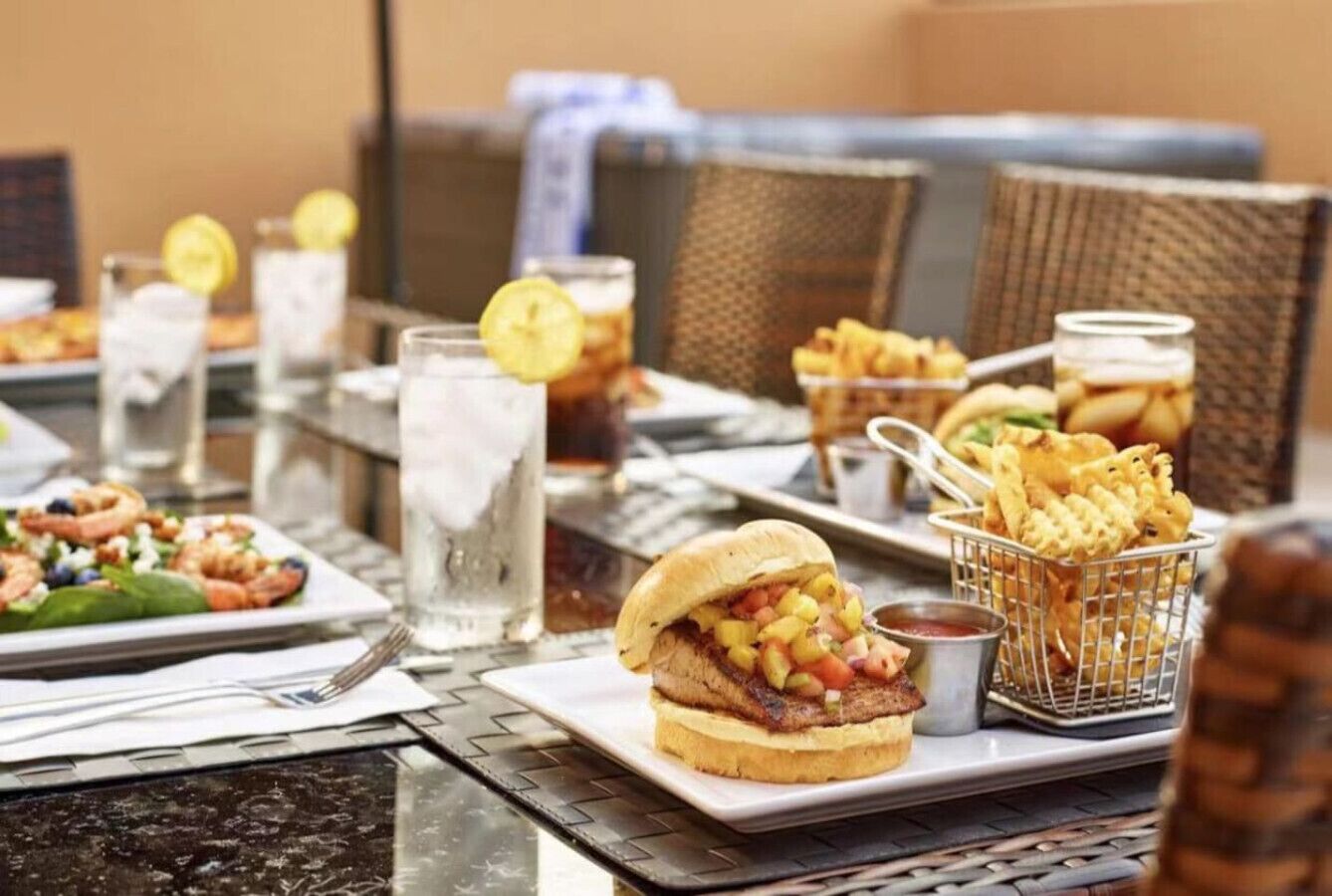 A dining table with food items, including a sandwich, fries, and a drink.