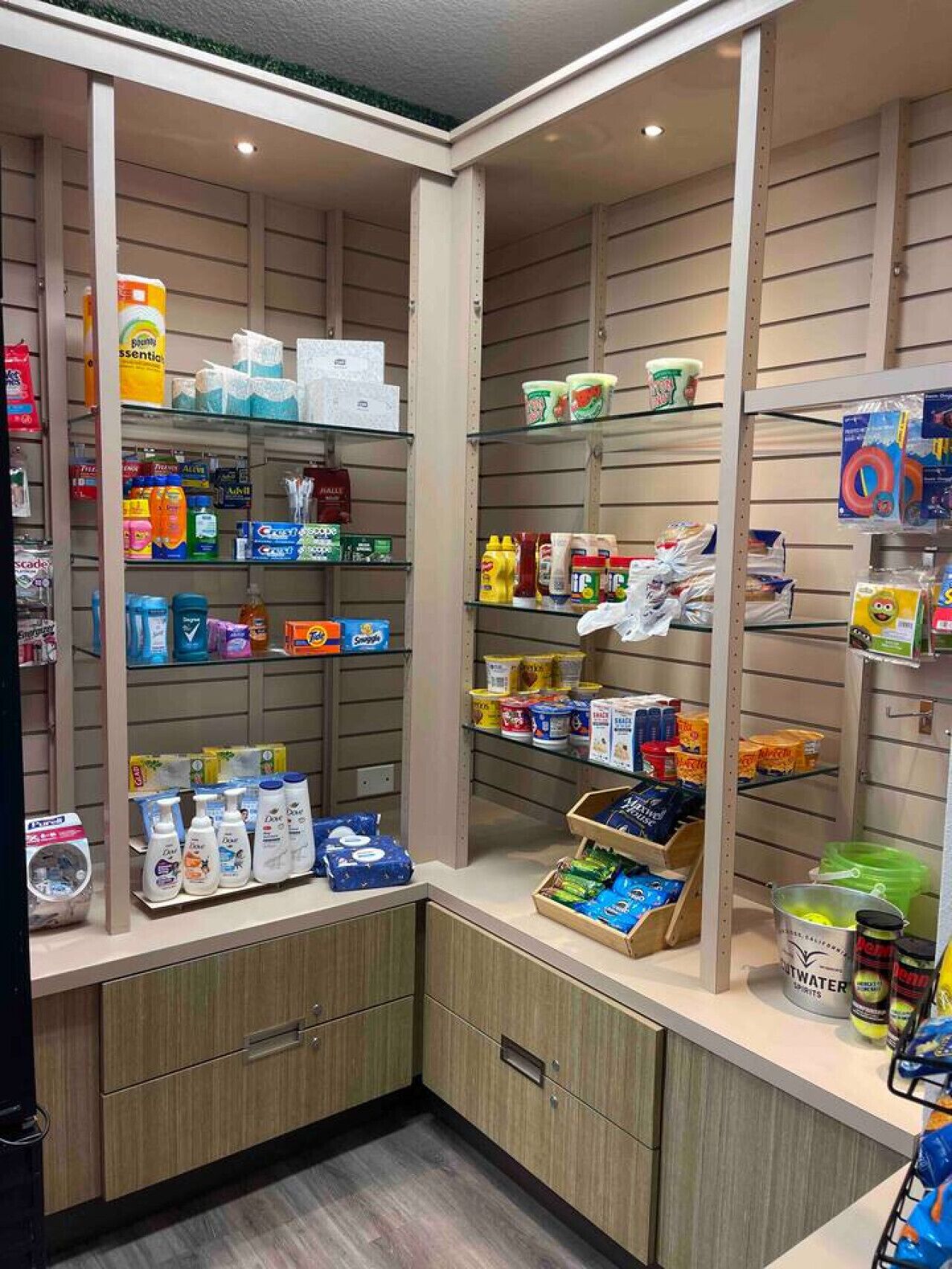 Una tienda bien organizada con estantes llenos de diversos productos, incluyendo artículos de aseo personal, aperitivos y bebidas.