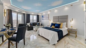 Una camera d'hotel moderna con un letto grande, una poltrona, un tavolo da pranzo e un soffitto decorato con nuvole.