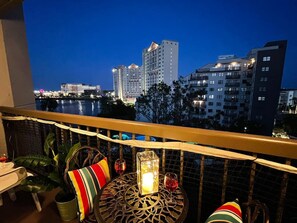 Ein Balkon mit Blick auf eine Skyline im Abenddämmerung, mit Hochhäusern und einem Gewässer.