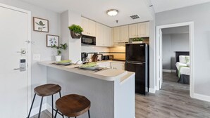 Een moderne keuken met een centraal eiland, barkrukken, een zwarte koelkast en een magnetron.