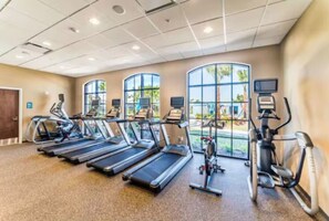 Ein Fitnessstudio mit Laufbändern, Crosstrainern und stationären Fahrrädern.