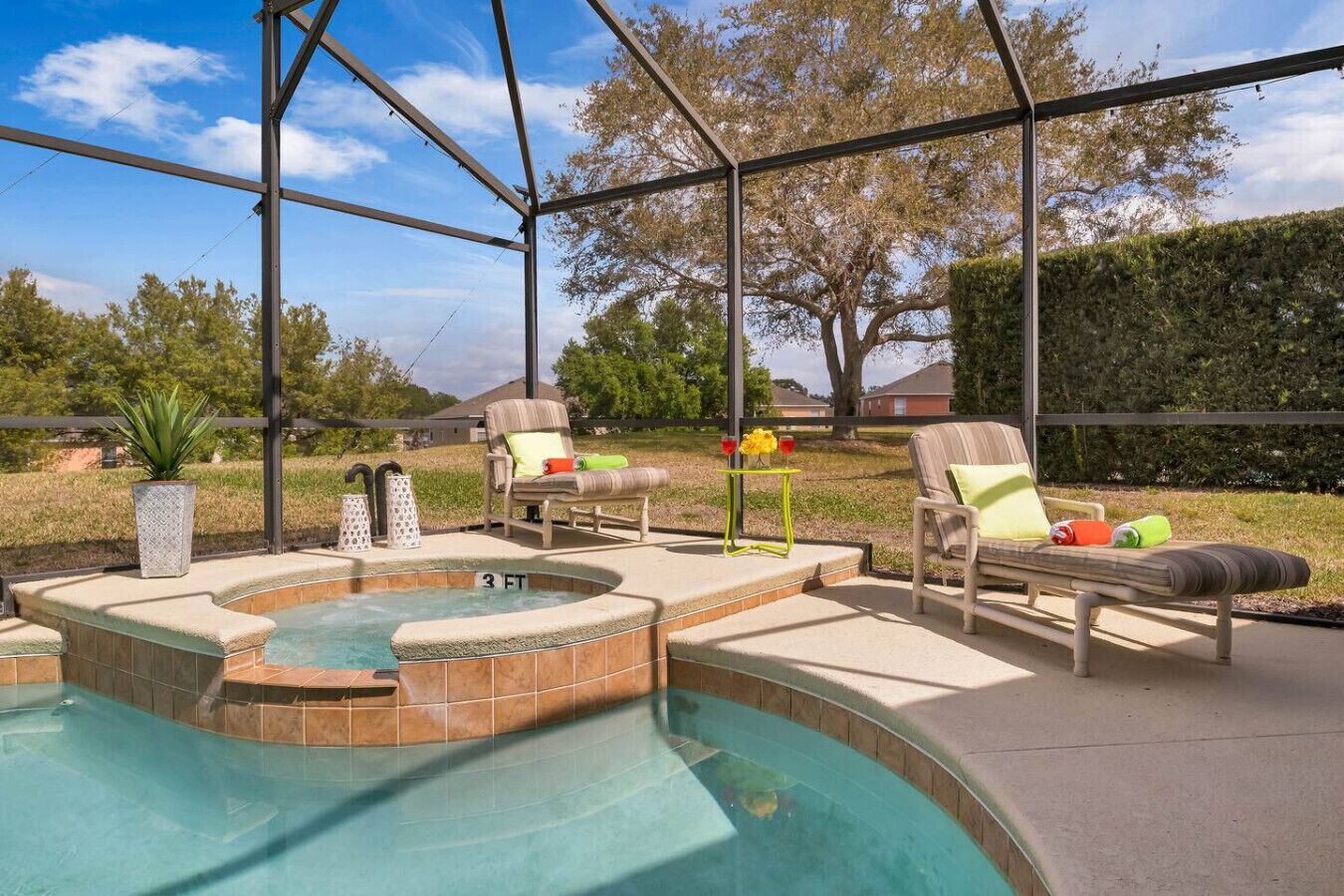 Un jardin avec un jacuzzi, deux chaises longues et une petite table avec des boissons.