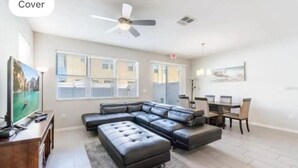 A modern living room with a sectional sofa, a ceiling fan, and a dining area with a table and chairs. - #5135 Cozy Villa 4/4 Centrally Located Disney/Epic (Kissimmee)