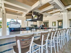 A modern kitchen with a large island, bar seating, and a flat-screen TV. - #1141 Two Resorts Waterside/Pool/Spa Disney Epic (Reunion)