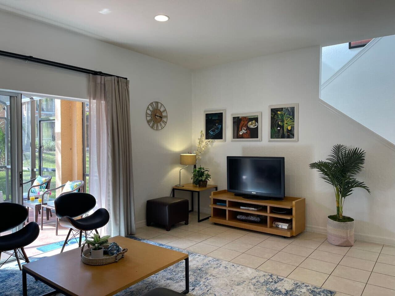 Una sala de estar moderna con televisor, asientos y una escalera.