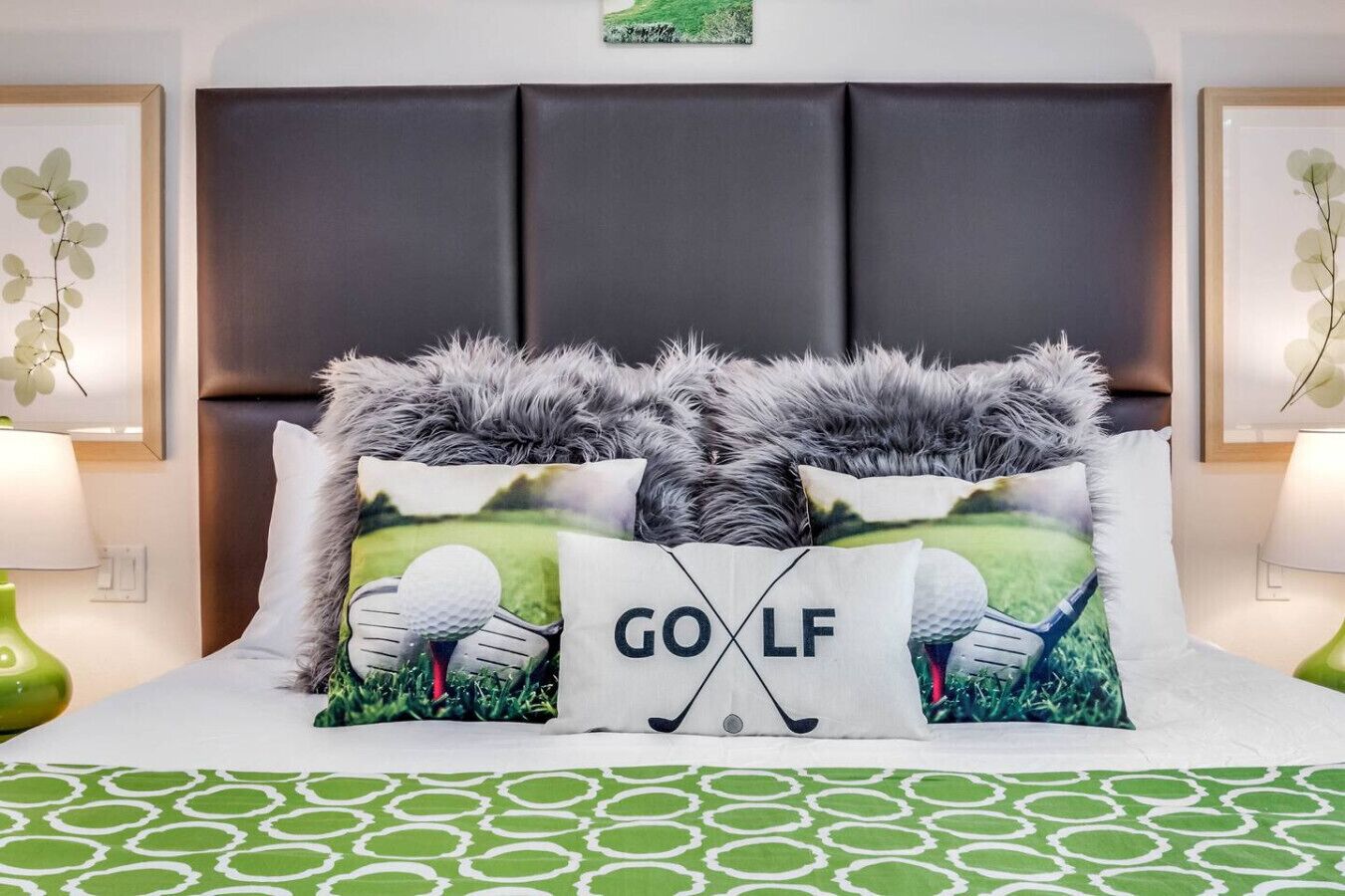 A bed with a green patterned bedspread, two pillows with golf-themed designs, and a dark headboard.