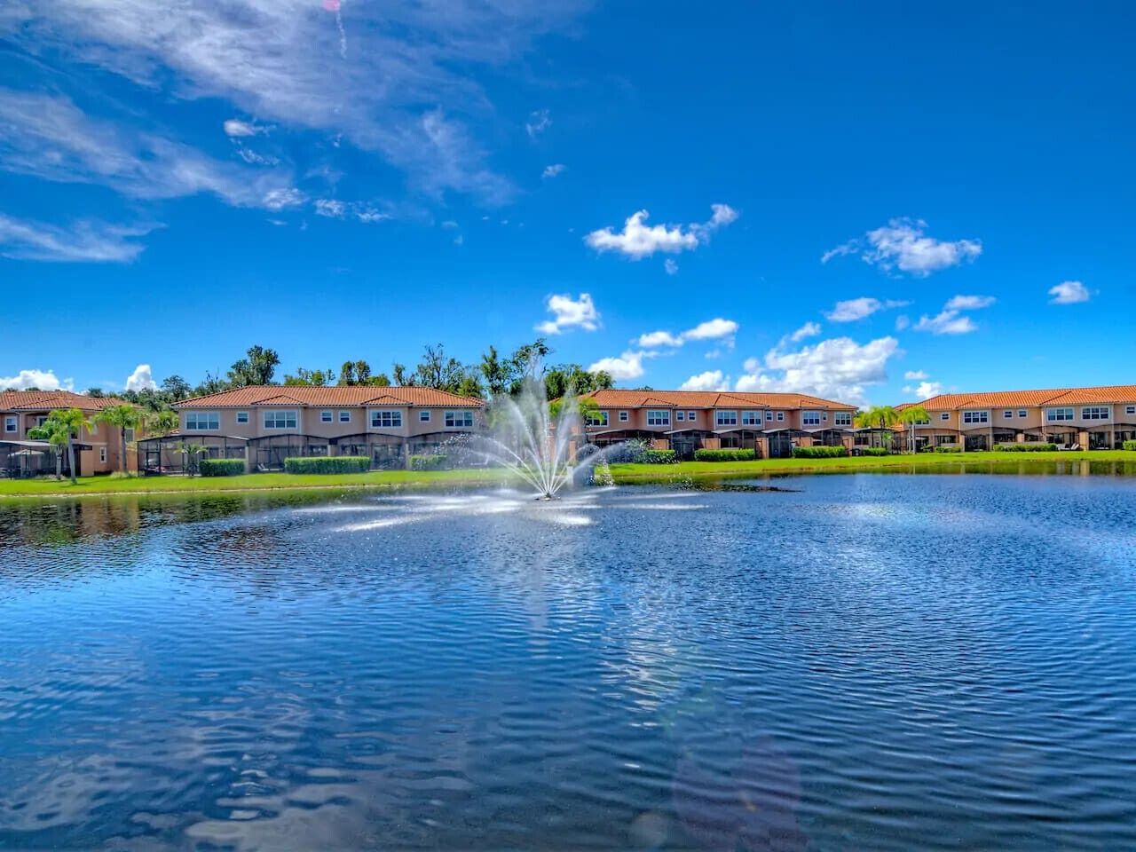A residential area with a fountain in the middle, surrounded by houses with red roofs.