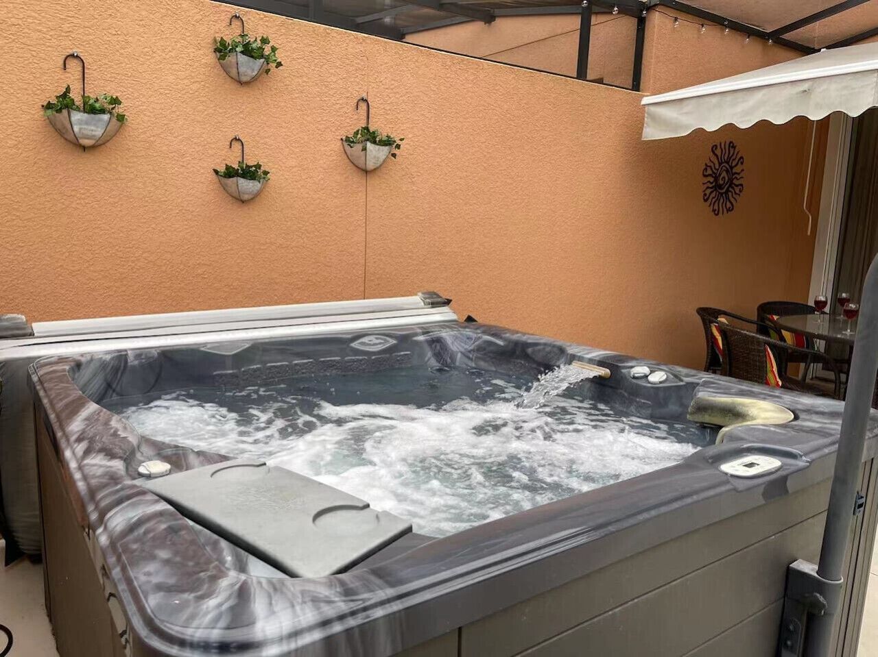 A hot tub with a clear water surface, surrounded by a beige wall.