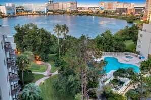 A hotel with a pool surrounded by lush greenery and a view of a large body of water. - 1902 Luxury 2BD/2BA Lakefront• I-Drive+Universal (Orlando)