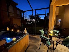 Ein Whirlpool mit Kerzen, ein Tisch mit Stühlen und Blick auf den Sonnenuntergang.