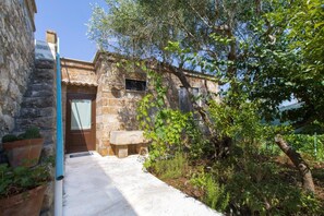 A stone building with a door, a bench, and potted plants. - Villa 'I Sogni Di Venere' with Sea View, Wi-Fi and Air Conditioning (Torre Suda)