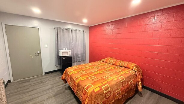A bedroom with a bed, a microwave, and a small table. - STARLITE MOTEL (Fraser)