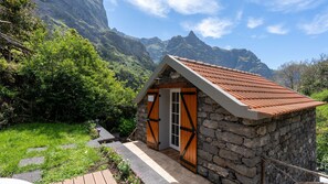 A stone cottage with a tiled roof, wooden doors, and a stone staircase leading to the entrance. - Stonewood Valley House by LovelyStay (Curral das Freiras)