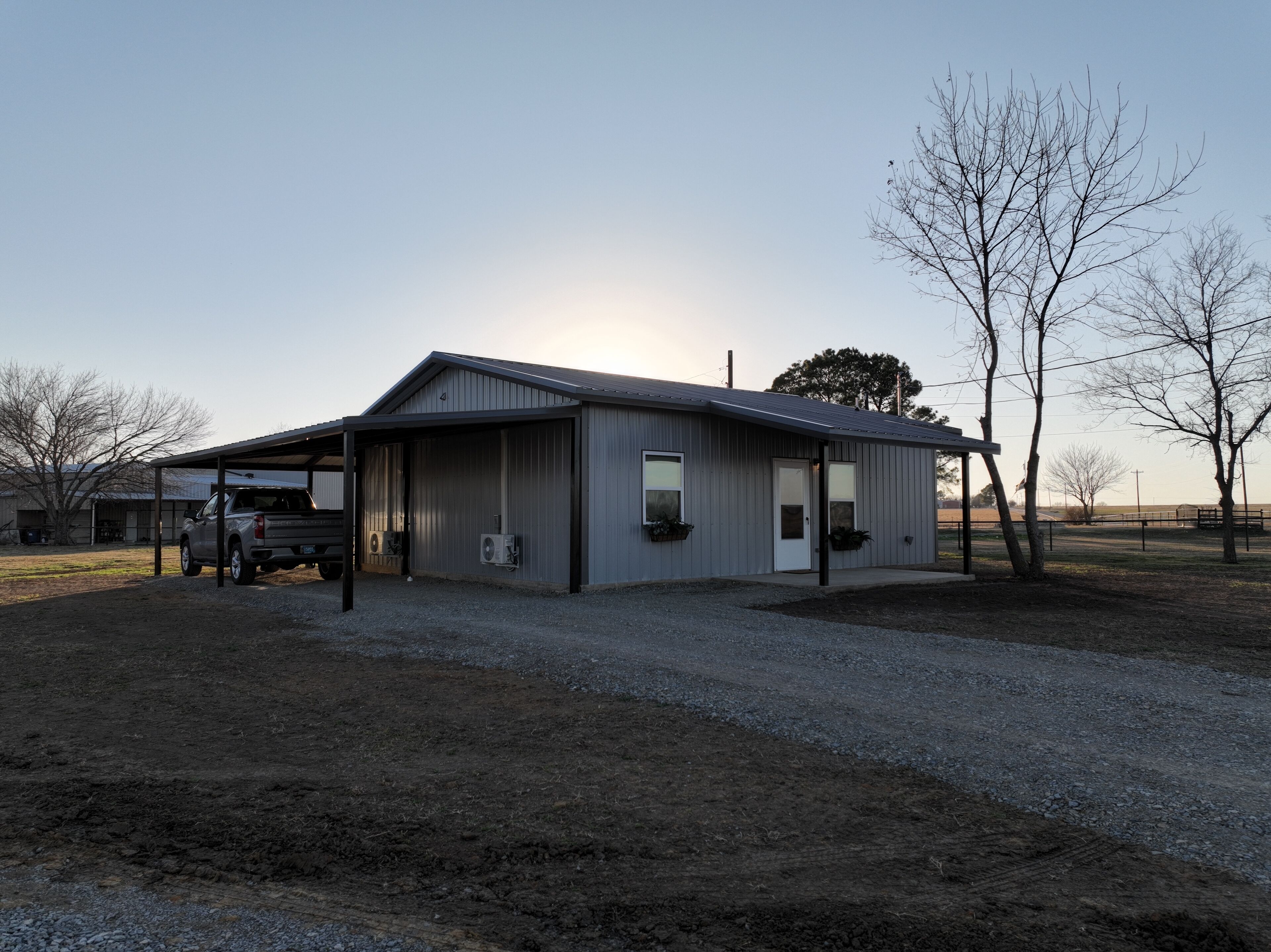 Un bâtiment métallique de plain-pied, doté d’une entrée abritée et d’un camion garé à l’extérieur.