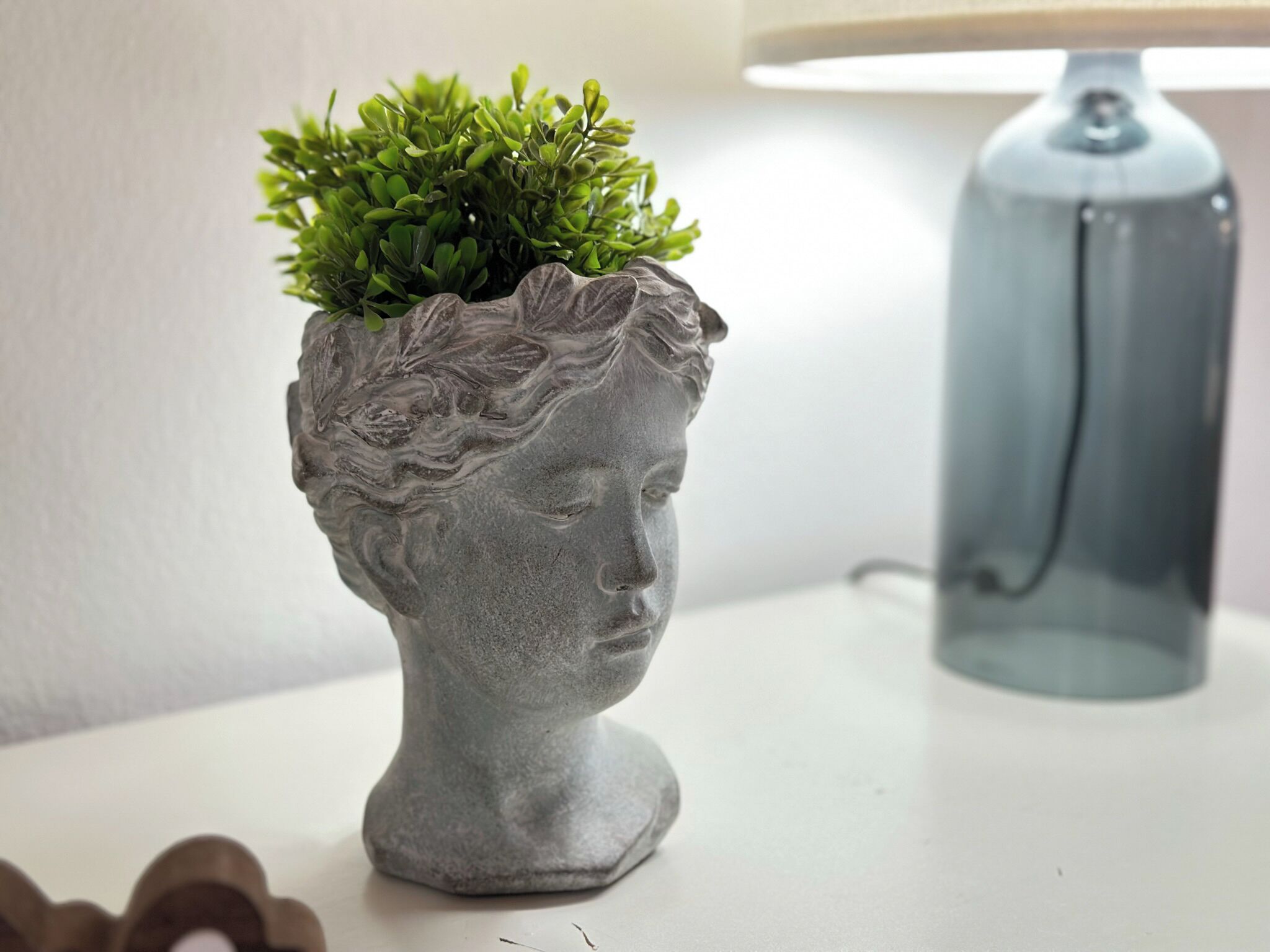 A sculpture of a head with a plant growing in the hair.