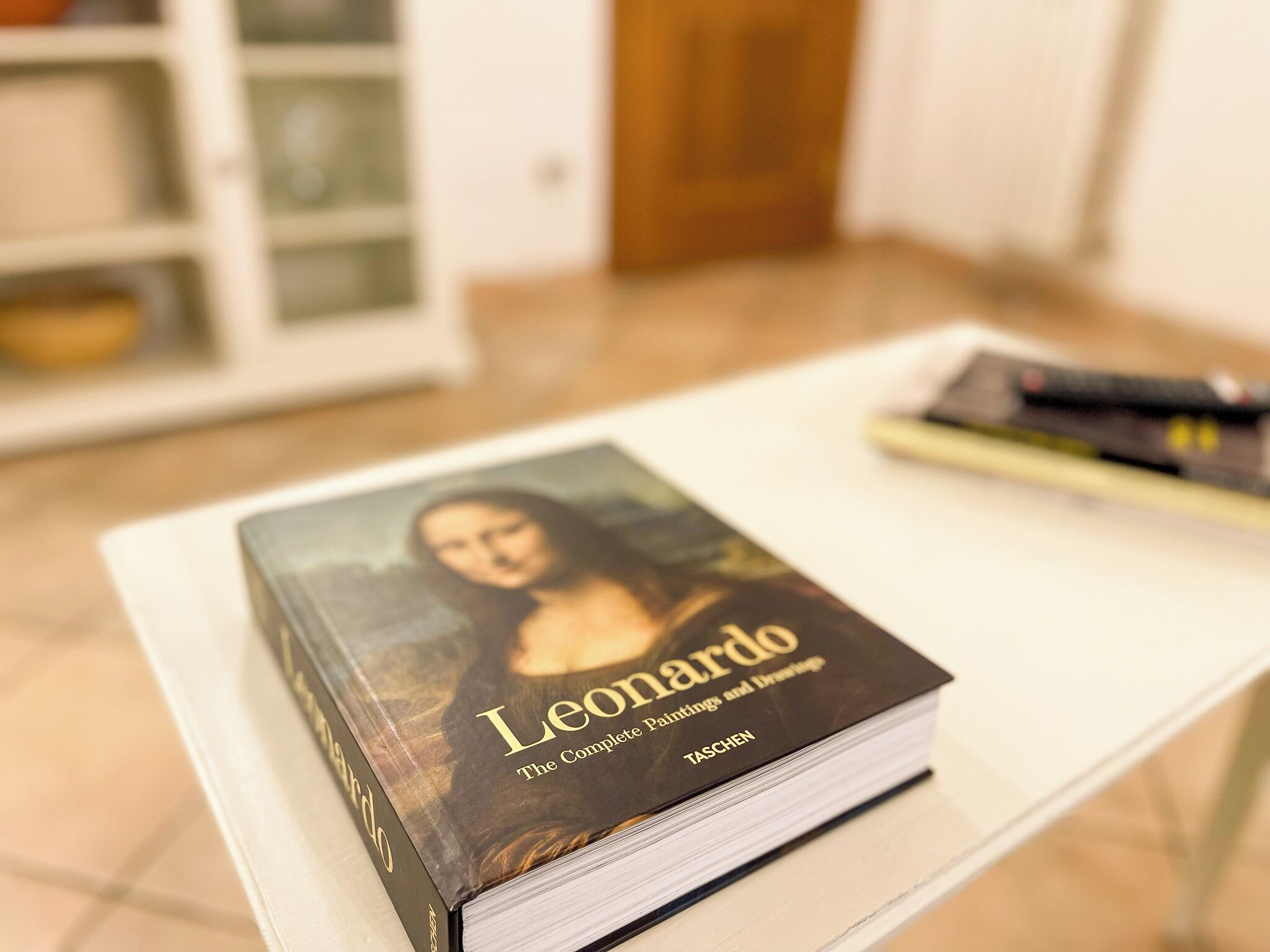 A book titled 'Leonardo: The Complete Paintings and Drawings' on a white table.