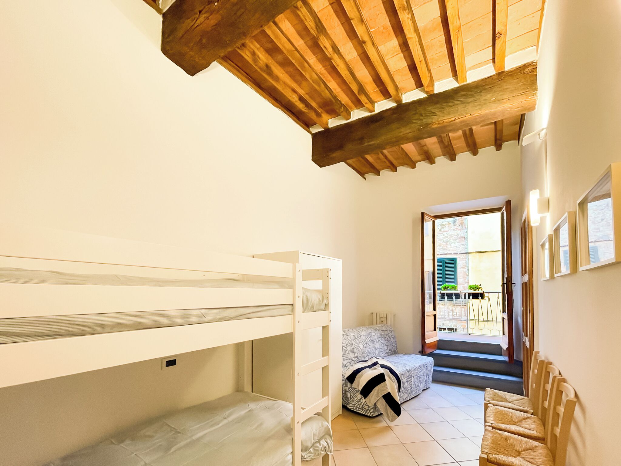 A small, cozy room with a bunk bed, a sofa, and a staircase leading to an outdoor area.