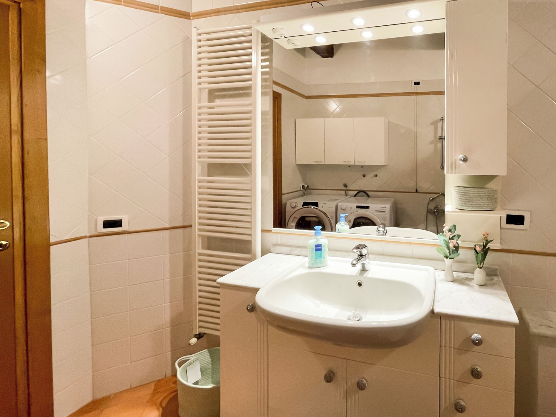 Un baño con lavamanos, espejo y toallero.