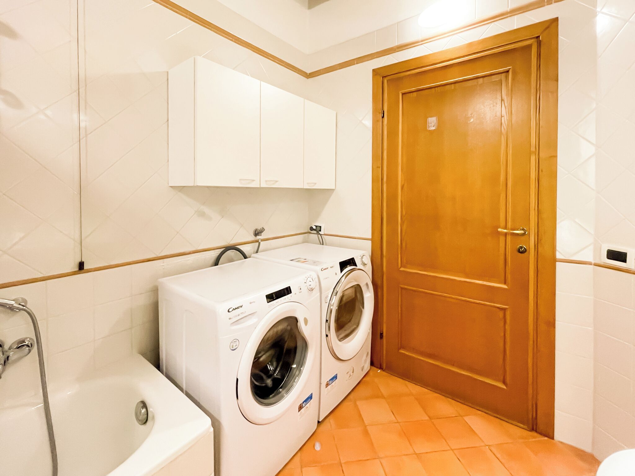 A laundry room with two washing machines, a sink, and a wooden door.