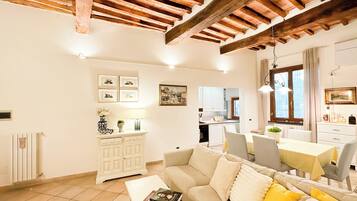 Ein geräumiges Wohnzimmer mit hoher Decke, einer Couch, einem Couchtisch und einem Essbereich mit Tisch und Stühlen.