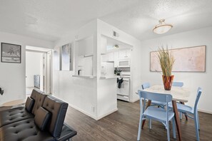 A modern living room with a sofa, a dining area with a table and chairs, and a kitchen with white cabinets and appliances. - Quiet Central Austin Getaway Near UT (Austin)
