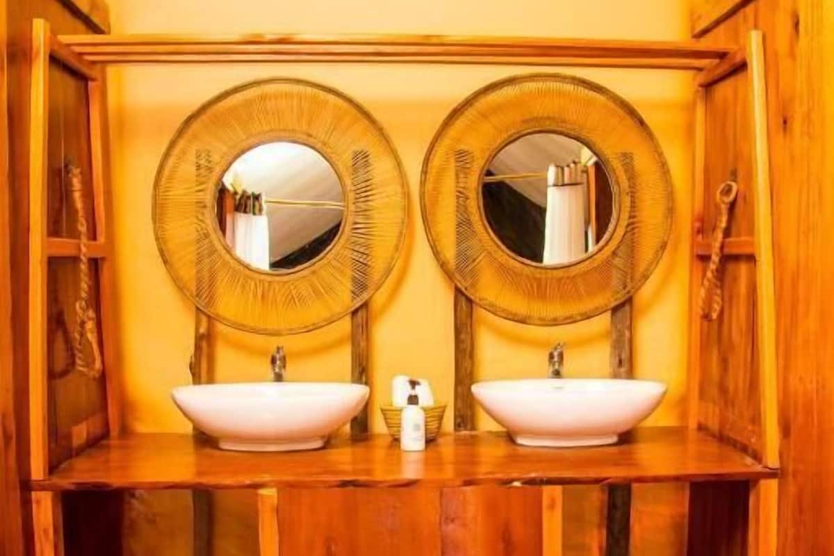 Ein Badezimmer aus Holz mit zwei runden Spiegeln, einem weißen Waschbecken und einem Holzregal.