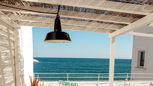 Eine Terrasse mit Tisch für zwei Personen, mit Blick auf das Meer.