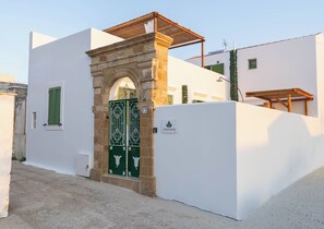 A villa with a white exterior, a stone archway entrance, and a green gate. - Villa with private pool, ideal for families and groups of friends. (Koskinou)
