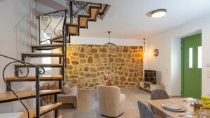 Un comedor con pared de piedra, una escalera y una puerta verde.