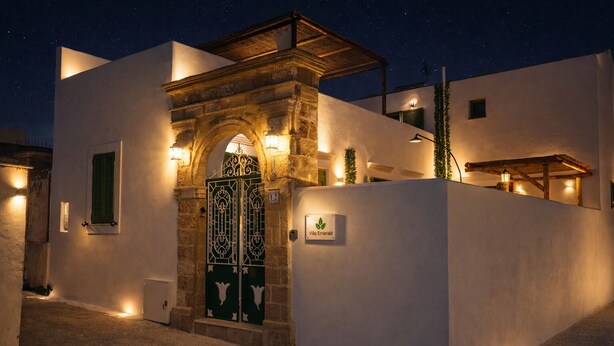 Un edificio con entrada de piedra, una puerta verde y un letrero que dice "Villa Emerald".