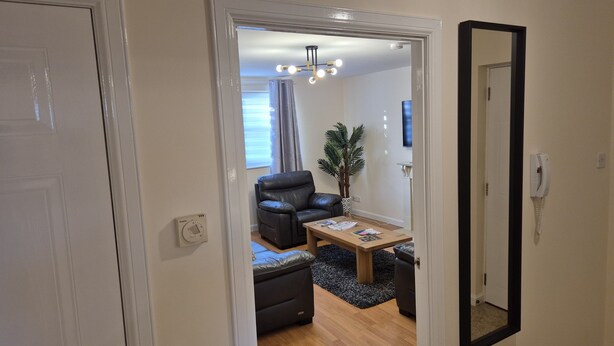 A living room with a black leather sofa, a wooden coffee table, and a potted plant. - Spacious Modern 2-BR Apartment in Aberdeen City Centre (Aberdeen)
