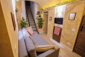 Ein gemütlicher Wohnbereich mit einer Couch, einer Treppe und einem Fernseher.