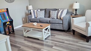 A living room with a gray sofa, a coffee table, a chair, a clock, and a ceiling fan. - Spacious NEW townhome w/Fast WiFi and parking (Glendale)