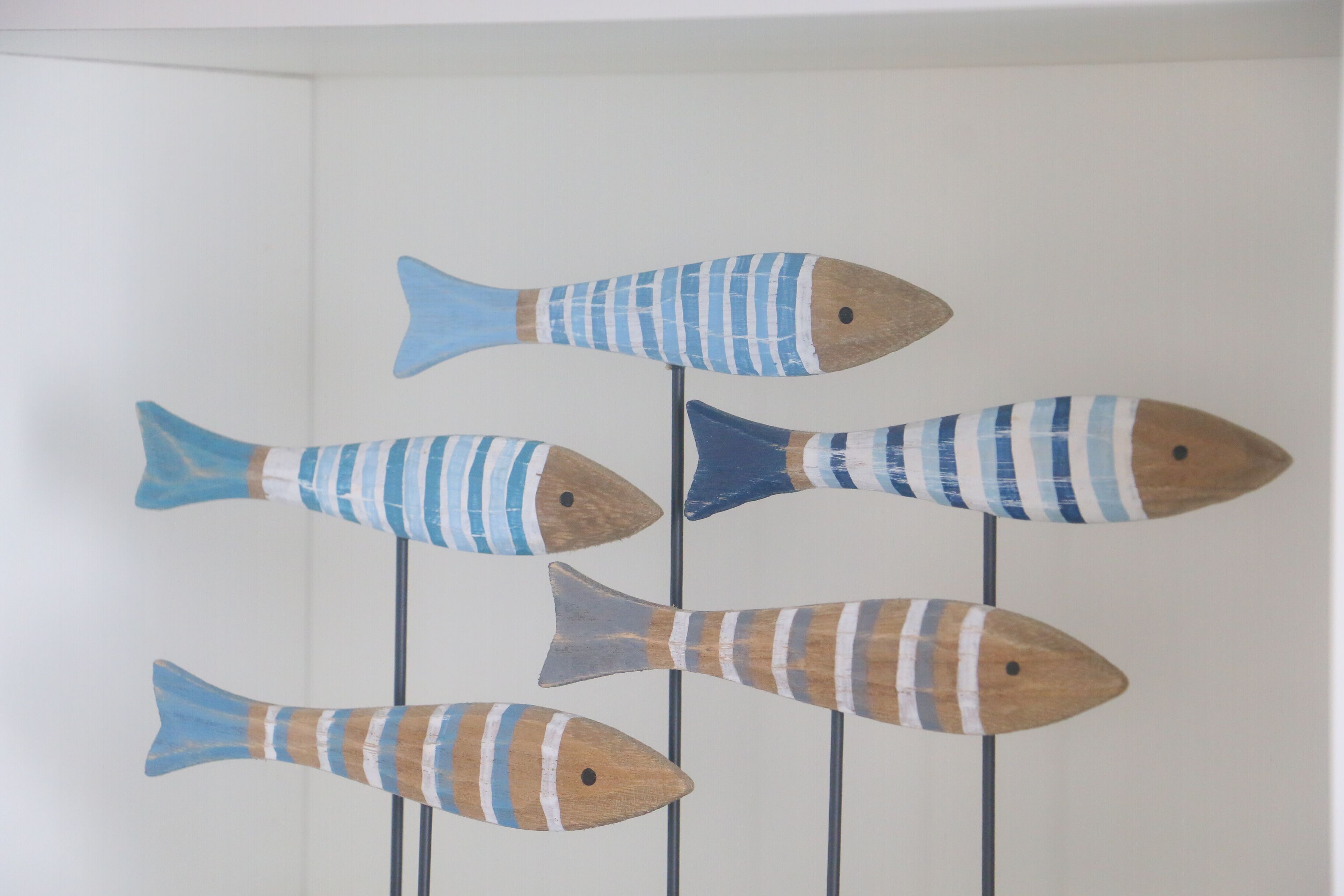 A wall with five wooden fish sculptures.