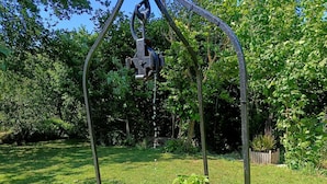 A garden with a metal structure, a bowl, potted plants, and a stone base.