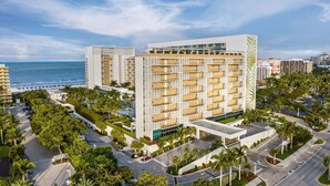 Un hotel moderno con varios pisos, un patio central y vista al océano.