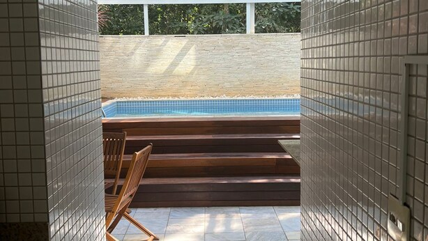 Ein modernes Badezimmer mit einer Glaskonstruktion für eine Hot Tub, Holzstufen und gefliesten Wänden.