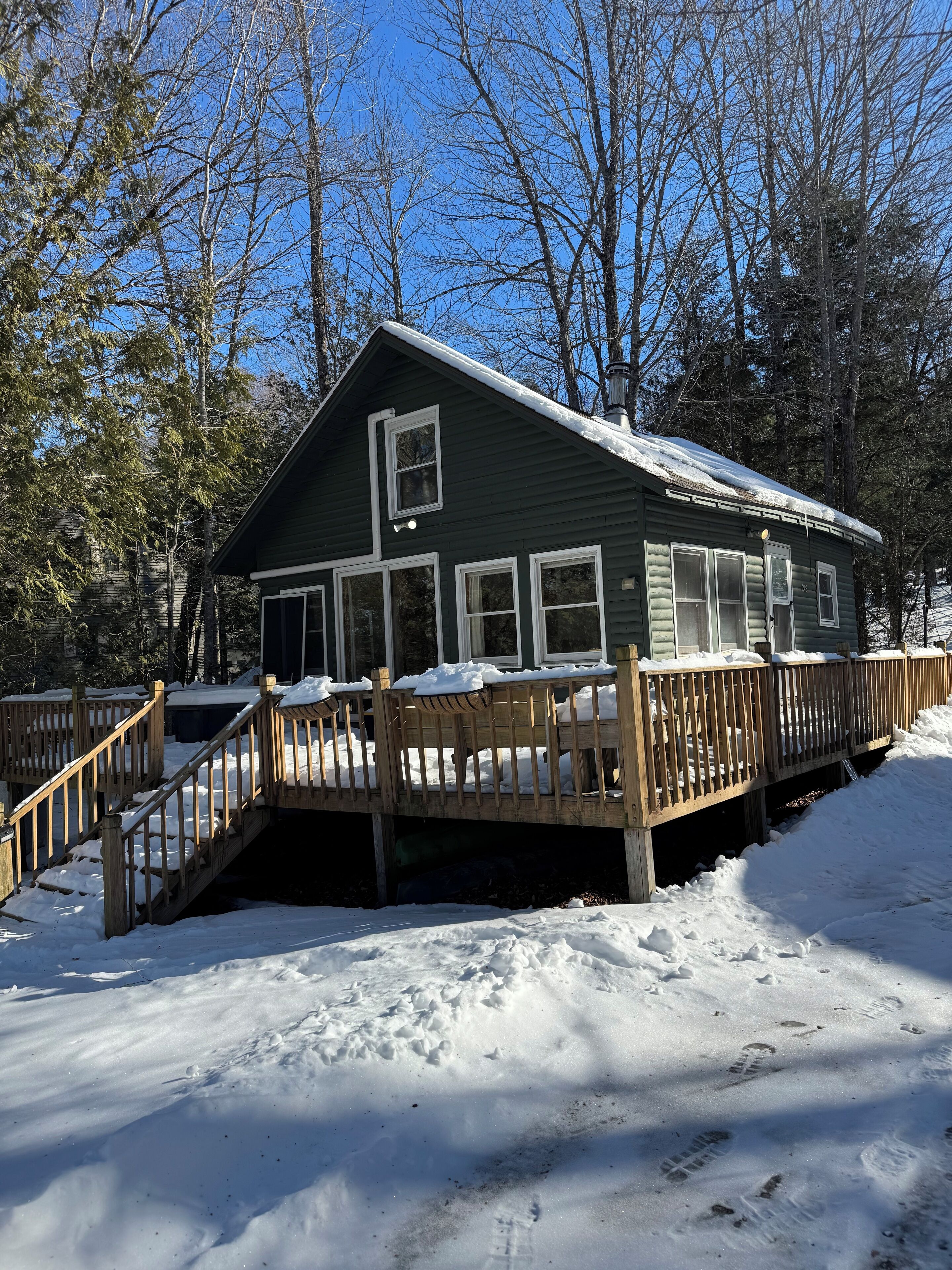 A cabin with a wooden deck and a staircase leading to the entrance.