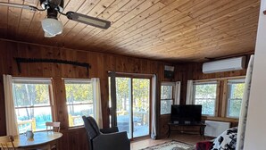 Interno di una baita di legno con zona pranzo, divano e televisione.