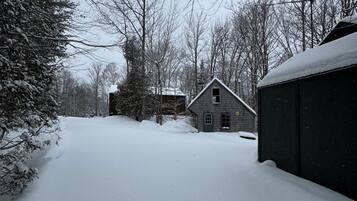 A snow-covered yard with a wooden house and a shed.