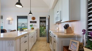 Een keuken met witte kasten, een centraal eiland, een koelkast en een eetgedeelte met uitzicht.